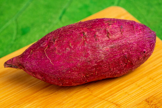 Batata-doce rosa sobre t&aacute;bua de bamboo 