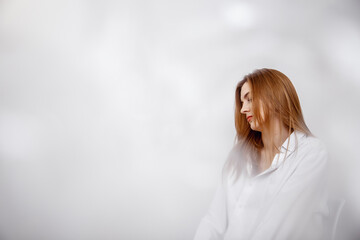 Fototapeta premium Businesswoman confident portrait. Fashion shoot of young sexy in white studio street style. Fashion photo. Caucasian female with long hair. Close-up portrait of a beautiful girl of the European race.