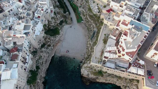 polignano a mare aerial shot drone at sunrise top down view tilt up from the sea to the cityscape