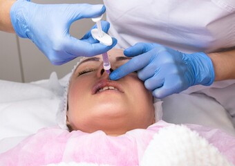 Cosmetology, lip augmentation, beauty injections in a beauty salon, close up