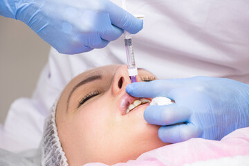 Naklejka premium Cosmetology, lip augmentation, beauty injections in a beauty salon, close up
