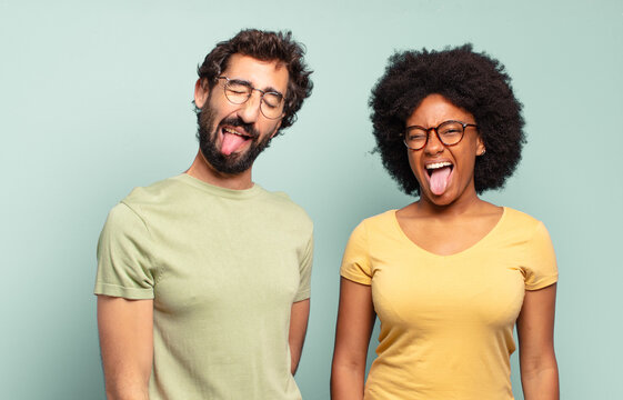 Multiracial Couple Of Friends With Cheerful, Carefree, Rebellious Attitude, Joking And Sticking Tongue Out, Having Fun