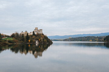 Fototapeta na wymiar Castle and colorful trees near lake with reflection