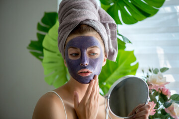 Young woman with violet shiny glamor face mask on her face.
