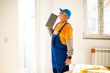 A middle-aged painter paints the walls in a building