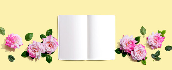 White blank notebook with pink roses overhead view - flat lay
