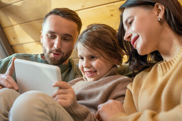 Happy young family in casualwear watching movie inside their country house