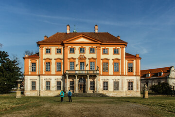 Tourists in Libechov, old abandoned baroque castle in central Bohemia,Czech republic.Romantic building with balcony,red facade and park.Rebuilt as Renaissance chateau.Sightseeing on sunnny day.