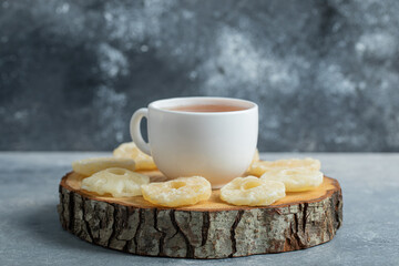 A cup of aroma tea with dried pineapple on a dark background