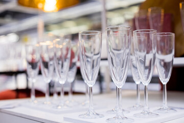 Rows of shiny empty high glasses with reflections in restaurant. Catering concept.Set of blank empty wine glasses displayed in rows. Preparation for the holiday.selective focus