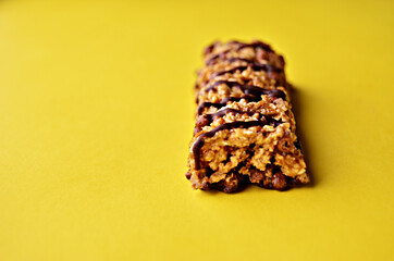One bar of granola with chocolate on a yellow background close-up with copy space. High quality photo