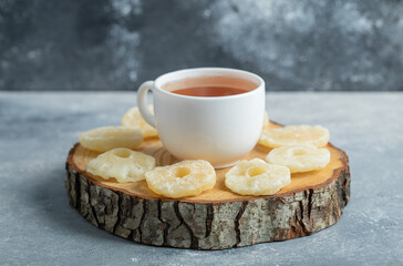 A cup of aroma tea with dried pineapple on a dark background