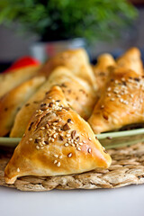 Samsa oriental Uzbek puff pastry pies with meat and pumpkin on a plate on the table, close-up. Triangular pies with sesame seeds, national authentic pastries