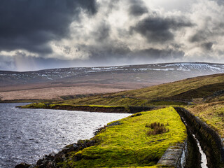 Angram reservoir with water course and the mountain of Great Whernside. Nidderdale. Yorkshire Dales National Park