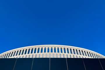 part of a circular building against a blue sky, an abstraction.