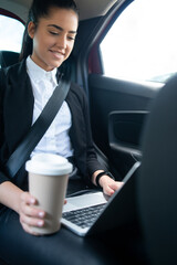 Businesswoman using laptop in car.