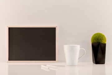 Modèle de tableau noir en ardoise avec espace vide pour logos, inscription publicitaire. Cadre en mode paysage sur un espace de travail avec une tasse et des craies.