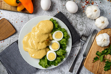 Traditional Peruvian food called Papa a la Huancaina made of cooked potatoes yellow pepper eggs on gray stone table Top View