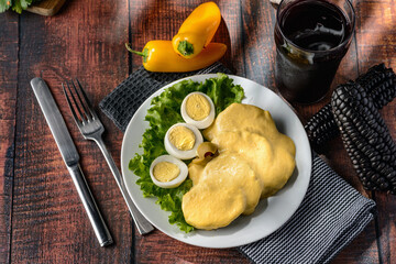 Traditional Peruvian food called Papa a la Huancaina made of cooked potatoes yellow pepper eggs on wooden table 