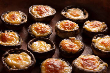 Roasted mushrooms with vegetables and parsley under melting cheese