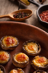 Roasted mushrooms with vegetables and parsley under melting cheese