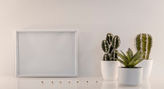 Modèle de cadre photo blanc avec espace vide pour logos, inscription publicitaire. Cadre en mode paysage sur un espace de travail avec des plantes vertes. Ambiance zen.