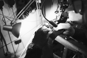 hands of craftsman sew leather with sewing machine. black and white photos