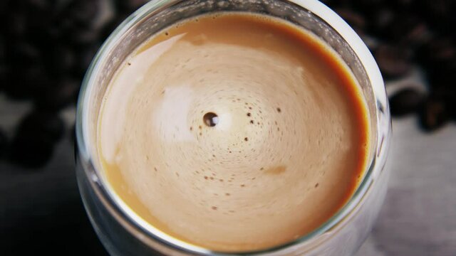 Flat ley close-up a cup of coffee with milk, a funnel that spins. There are many coffee beans lying next to it.