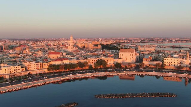 aerial shot of bari city at sunrise, drone flying up from the sea revealing old town skyline at dawn