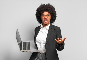 young afro businesswoman looking angry, annoyed and frustrated screaming wtf or what’s wrong with...