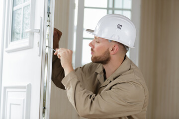 locksmith using screwdriver on door of residential property - obrazy, fototapety, plakaty