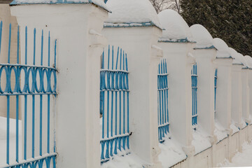 Fototapeta premium Stone fence of the church covered with snow caps
