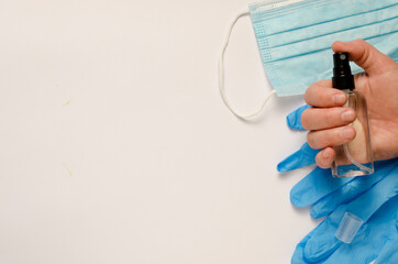 Hand sanitizer bottle in hand, medical mask, medical gloves on white background. Antibacterial liquid against 19-ncov.Call for hand disinfection. Stop coronavirus concept.Blurred background