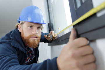 man measuring window prior to installation of roller shutter outdoors