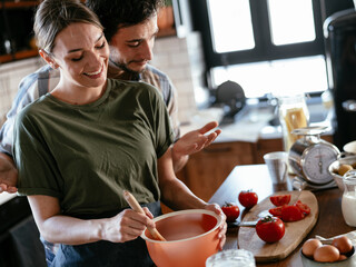 Husband and wife in kitchen. Young couple preparing delicious food at home..