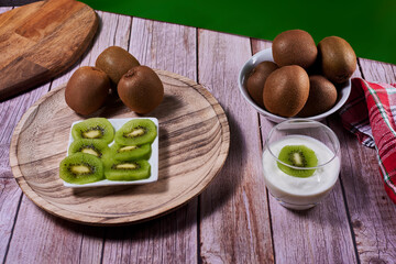 Yoghurt glass with kiwis on wooden plate