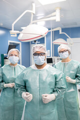 Fototapeta na wymiar Three contemporary surgeons in protective workwear preparing for operation