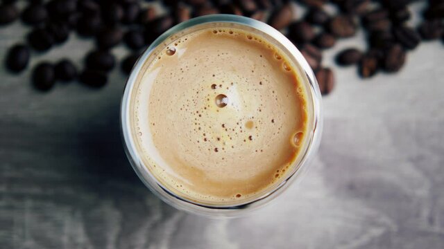 Flat ley close-up a cup of coffee with milk, a funnel that spins. There are many coffee beans lying next to it.