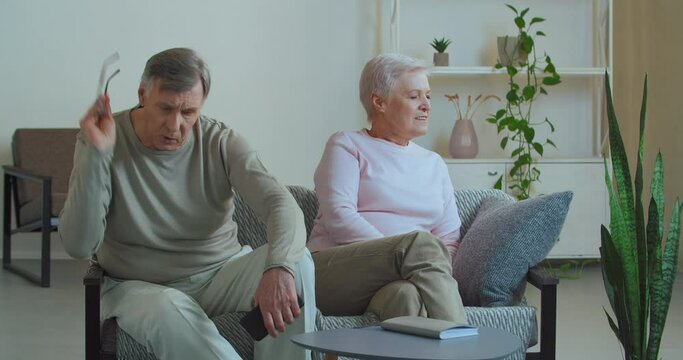 Elderly couple caucasian old wife and husband in glasses quarrel at home sitting on couch discussing problems feel resentment and misunderstanding mature man shouts actively gesticulates woman ignores