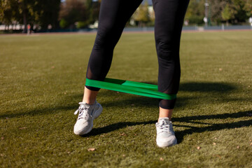 Fototapeta premium Girl exercising with a rubber band in the stadium