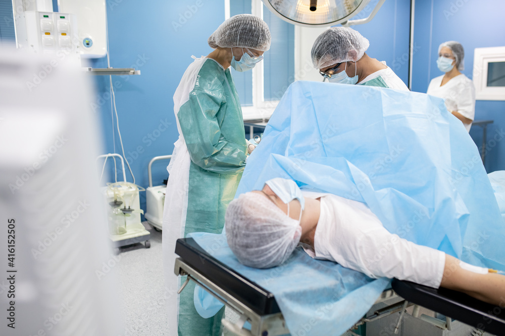 Aufkleber male patient lying on operating table while two surgeons preparing for operation