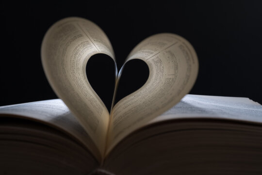 Close up heart shape from paper book on dark background. lights and shadows concept