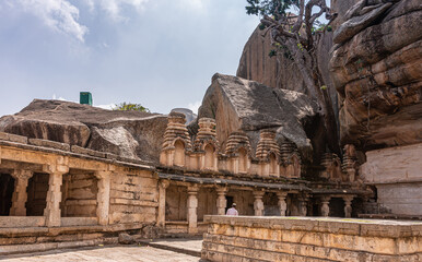 Chitradurga, Karnataka, India - November 10, 2013: Fort or Elusuttina Kote. Sampige Siddeshwara ruinous Shiva cave temple against boulders under blue sky.
