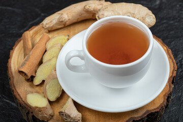 A cup of aroma tea with gingers on a wooden board