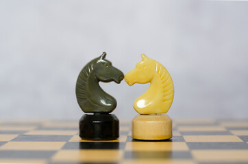 The black and white knights stand on the chessboard facing each other. Chess pieces, side view