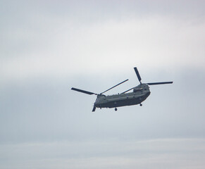 RAF Chinook UH-1 helicopter flying low in a cloudy blue grey and white winter sky