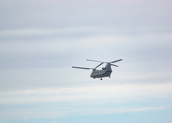 Fototapeta na wymiar RAF Chinook UH-1 helicopter flying low in a cloudy blue grey and white winter sky