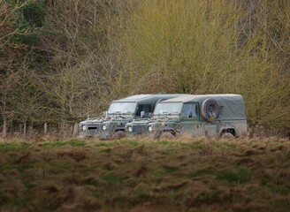 two parked british army land rover defenders 