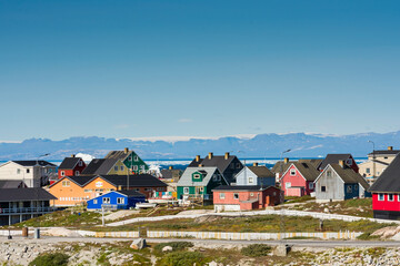 Greenland. Ilulissat. Colorful houses in town with the icy fjord in the distance.