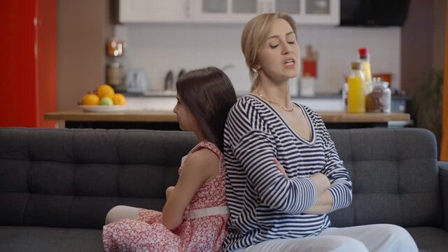 The girl and her mother are sulking and turning their backs to each other.Family conflict fight, parents and children feel angry after discussion concept.